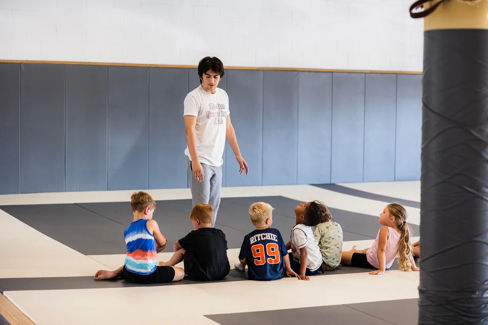 Oscar Lopez coaches young children during kids wrestling