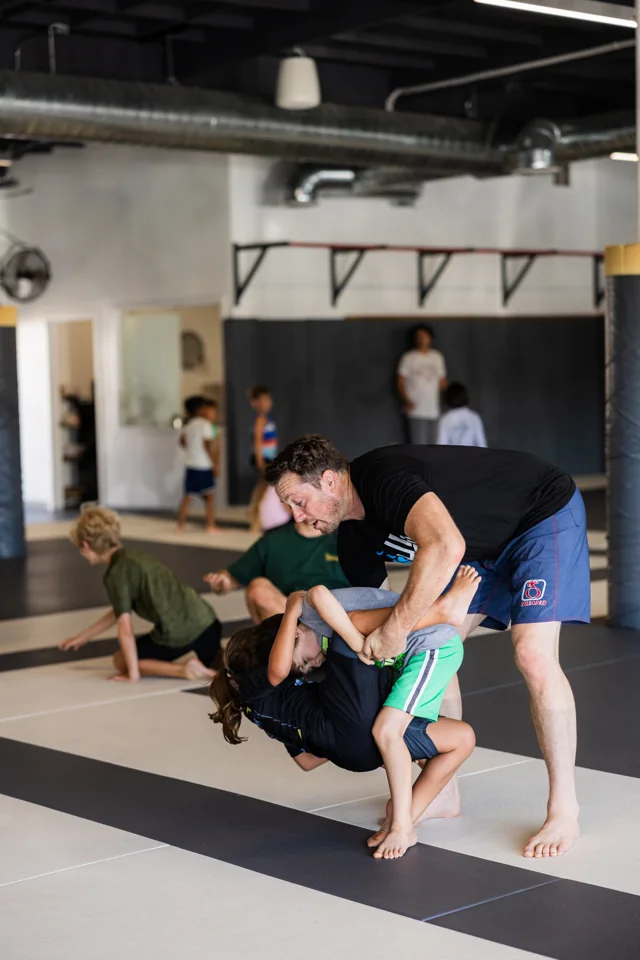 A coach lifts a child during kids class