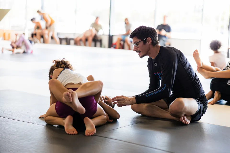 An instructor coaches two children during no-gi practice