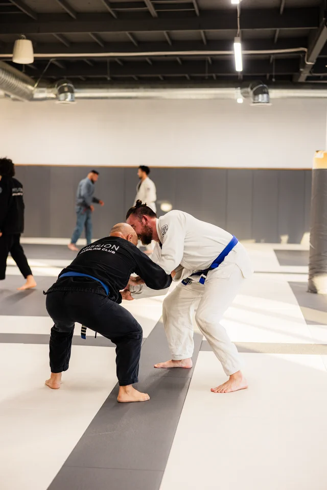 Two students in gis work a standing grappling exchange at Mission Grappling Club
