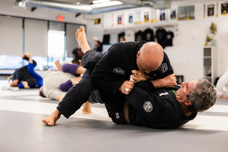 Two men in black gis grapple during adult training