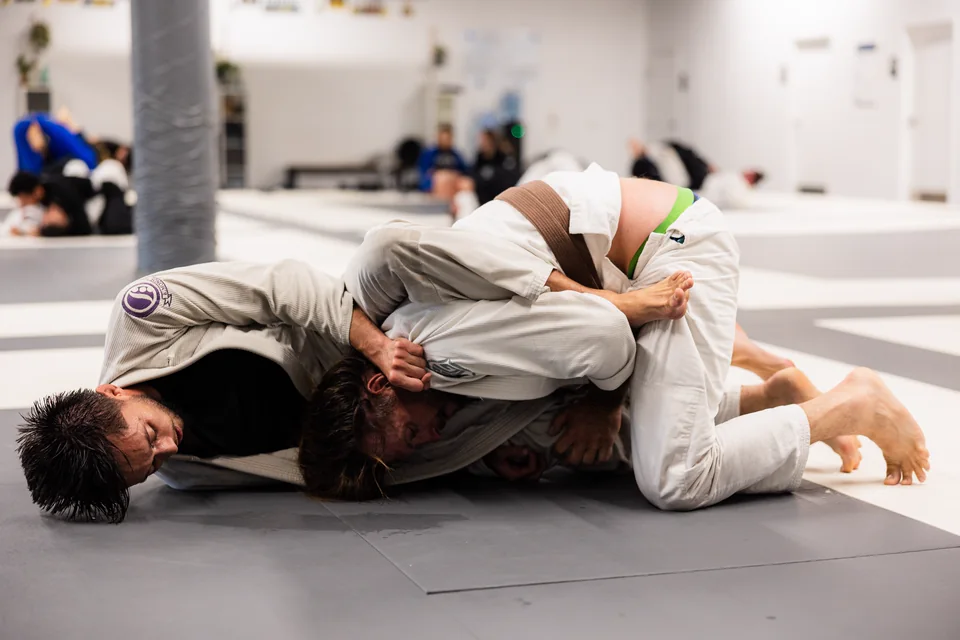 Two students in white gis grapple on the mats