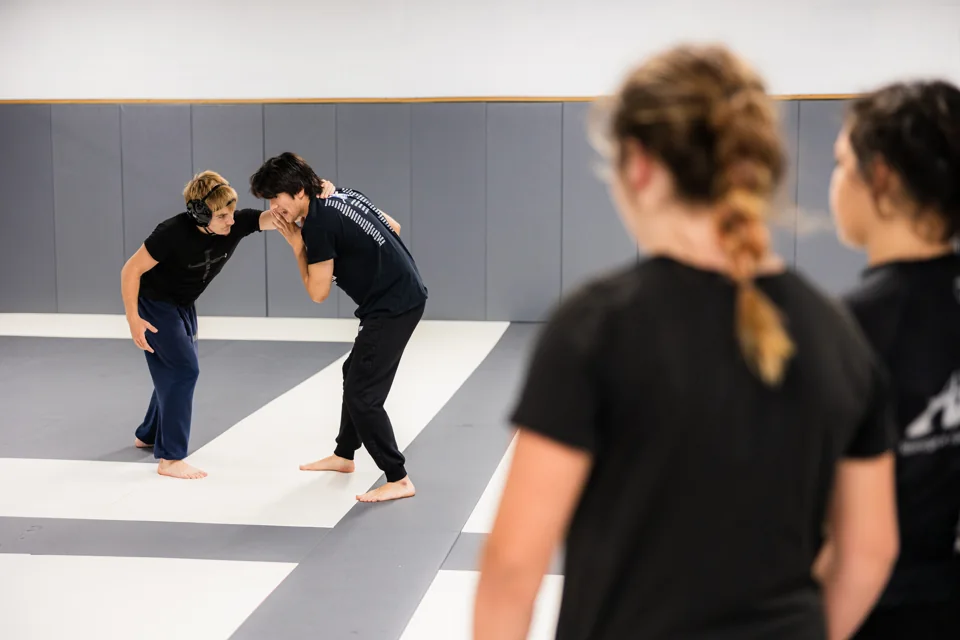 Two students practice a standing grip while others watch