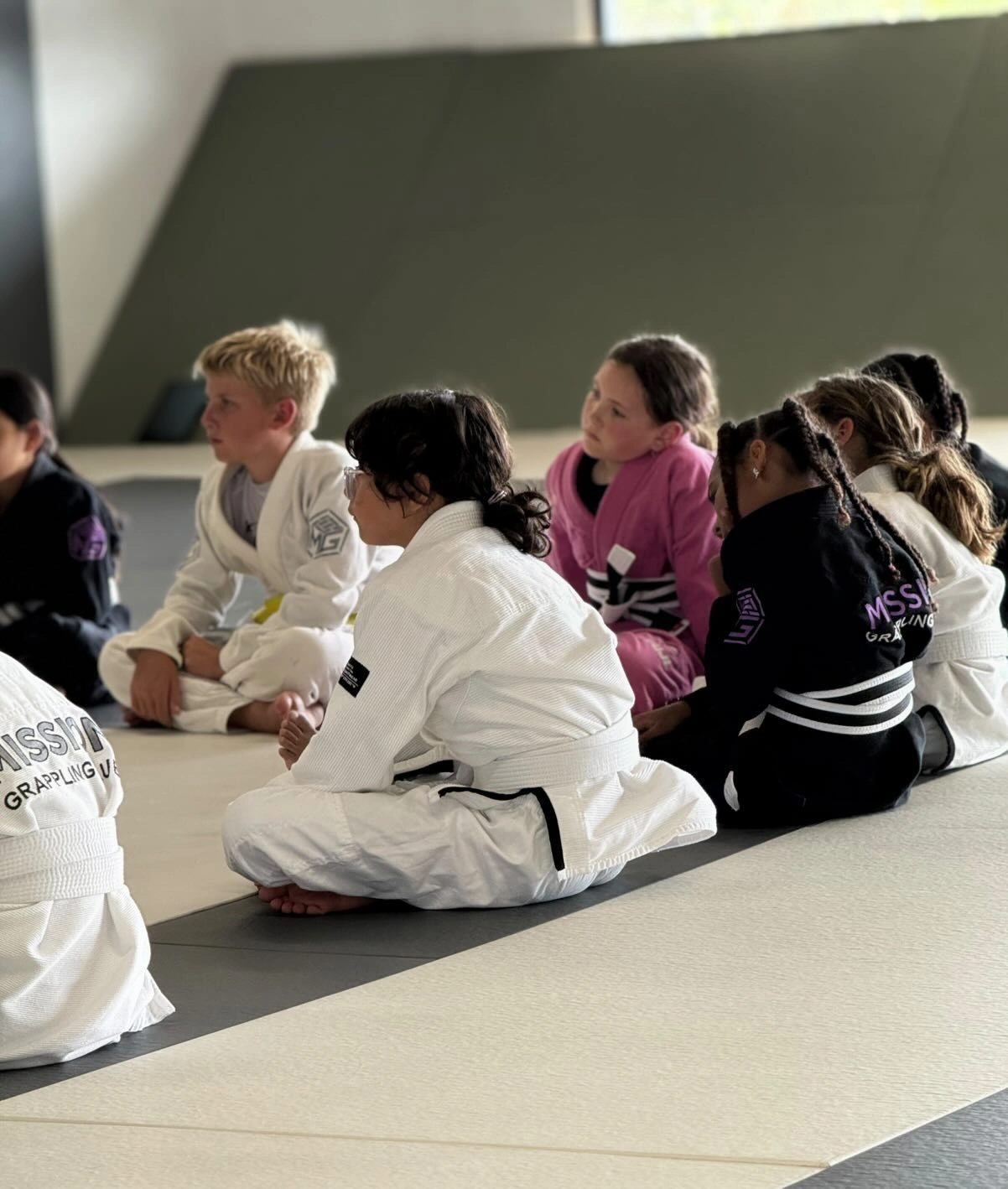 Kids Jiu-Jitsu students listening to instruction on the mats
